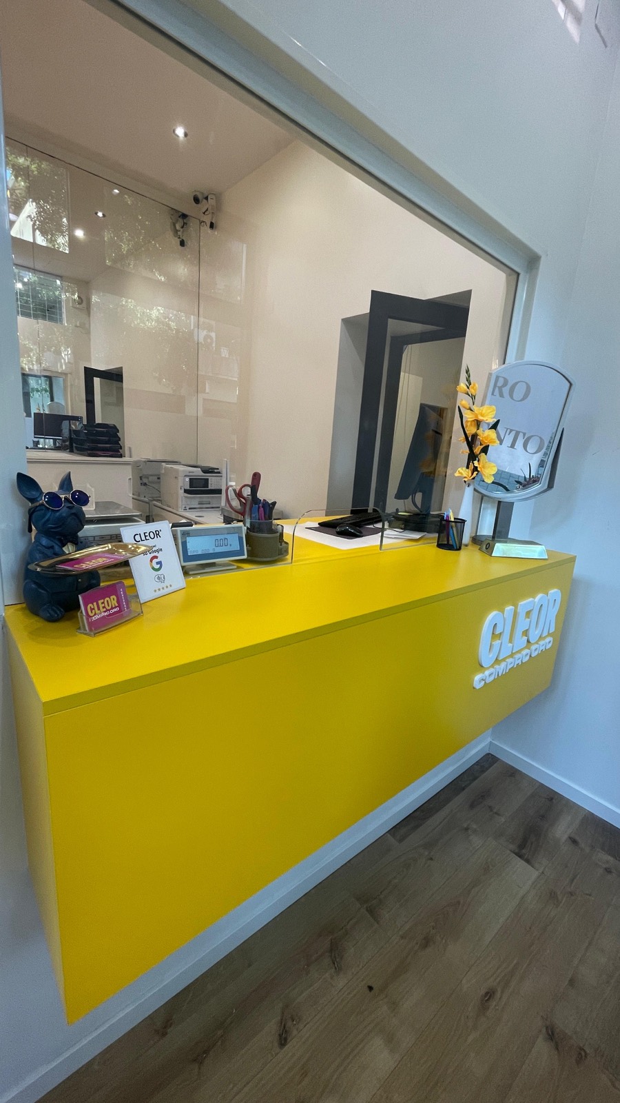 Il piano del bancone: bilancia con display verso il cliente, cartello delle recensioni Google e materiali Cleor