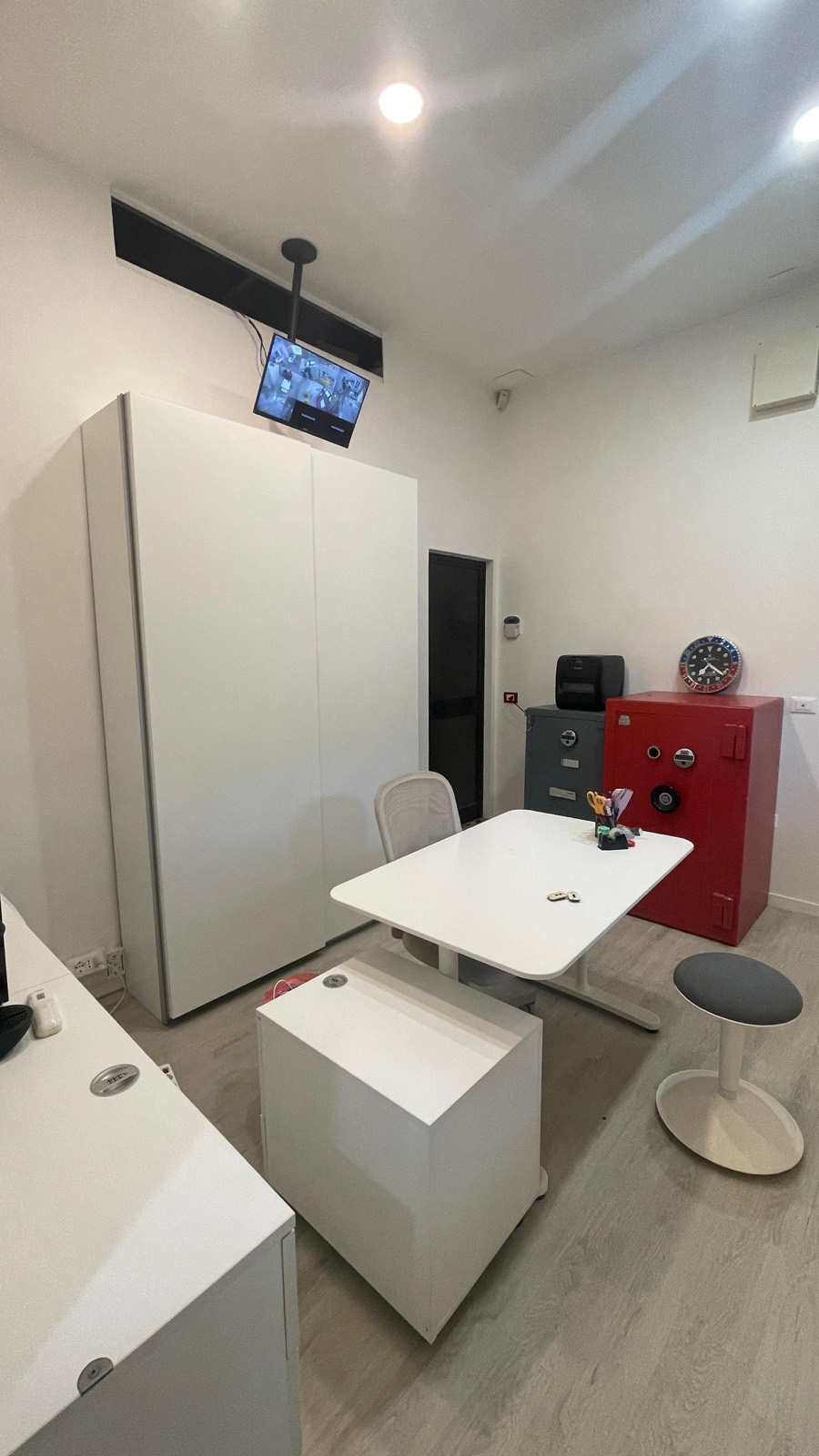 Il retro del negozio: armadio bianco, cassaforte e monitor della videosorveglianza
